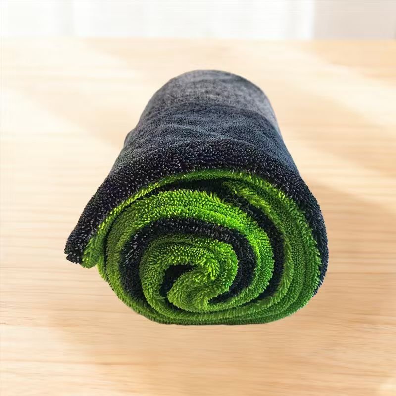 Serviette de séchage auto en microfibre grise et verte enroulée sur une table en bois