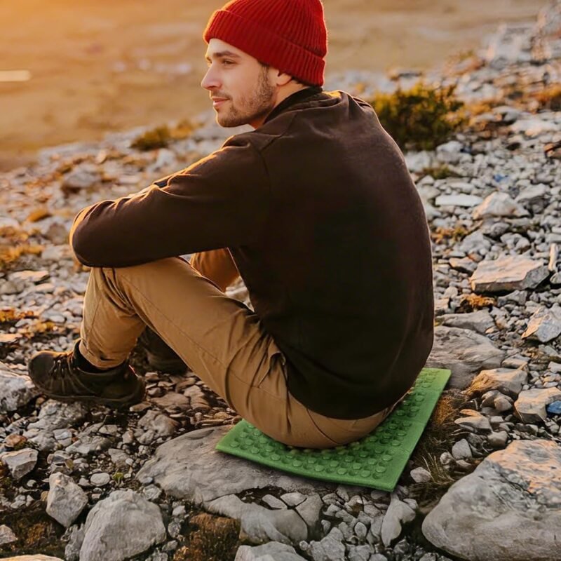 Randonneur assis sur une assise pliable en mousse alvéolée sur un sol rocheux