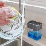 Distributeur de liquide vaisselle avec éponge à côté de l’évier pendant la vaisselle