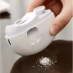 Coupe-ongles électrique tenu en main, vidant la poussière d’ongles sur une table