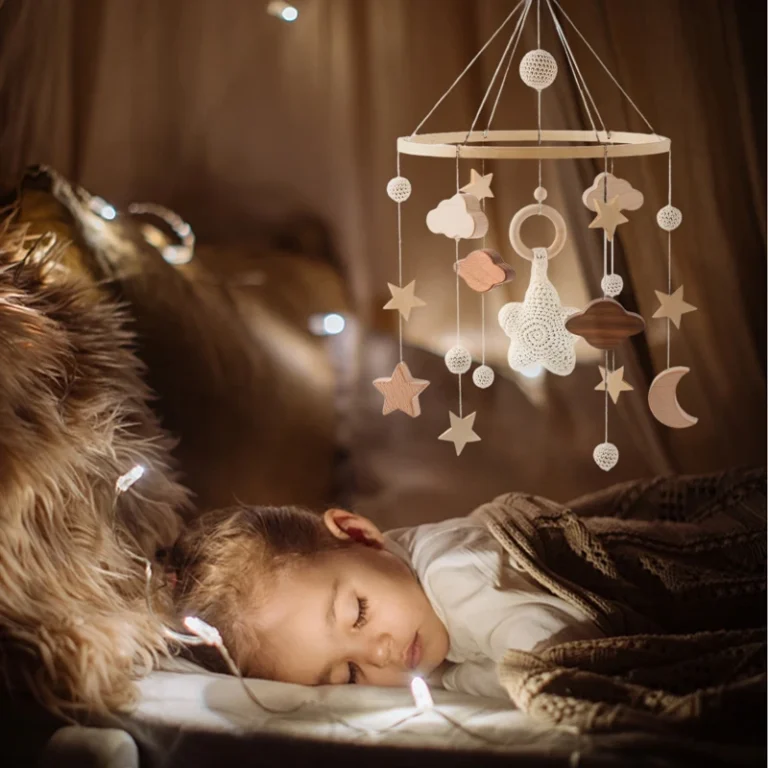 Mobile bébé en bois avec étoiles, nuages et lune suspendu au-dessus d’un enfant endormi