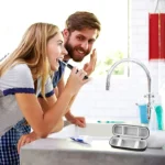 Étui de voyage rigide noir pour brosse à dents ouvert sur un plan de salle de bain