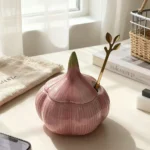 Pot en céramique rose en forme d’ail avec couvercle sur un plan de travail