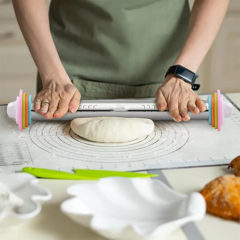 Rouleau à pâtisserie en acier inoxydable avec anneaux d’épaisseur colorés étalant une pâte sur un tapis de cuisson