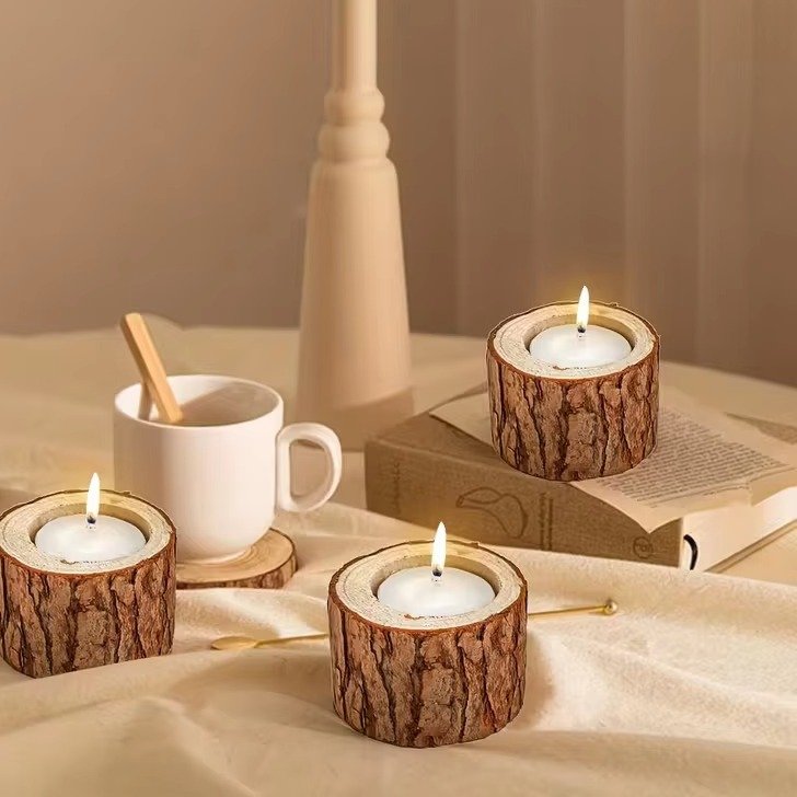 Trois photophores en bois en forme de souche avec bougies allumées sur une table